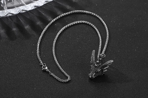 Détail d'un pendentif tête de dragon en acier inoxydable sur une chaîne tressée