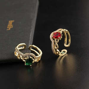 Detail of gold-plated open rings with ruby and emerald stones and pavé diamond link bands