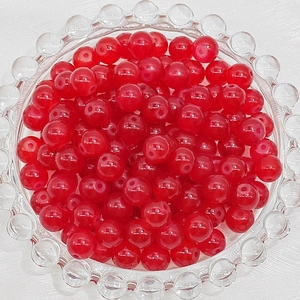 Close-up of 6mm translucent red glass beads for DIY jewelry making in a glass bowl