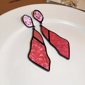 Detail of geometric asymmetric earrings with pink resin petals and black metal frames