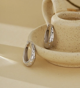 Detailed shot of 925 sterling silver star hoop earrings on a minimalist ceramic base