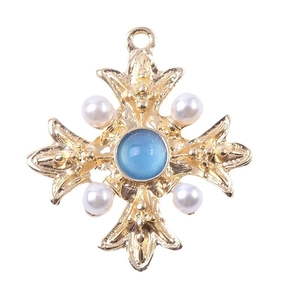 Vintage golden cross pendant with blue crystal and white pearls on white background