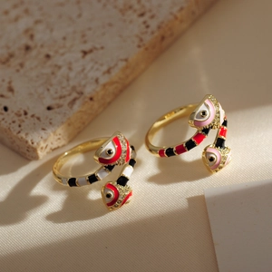Detailed close-up of gold-plated snake rings with colorful enamel on beige stone base