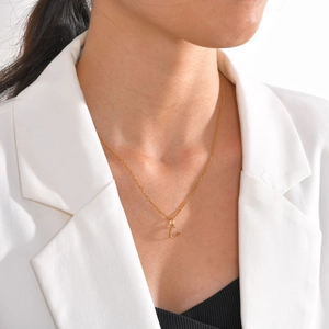 Close-up of a gold stainless steel letter C necklace with a small heart detail