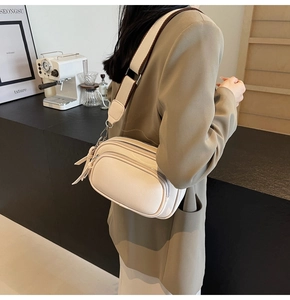 Crossbody bag in cream white PU leather with wide shoulder strap shown on a model