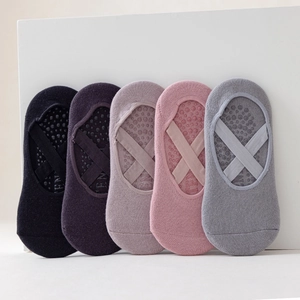 Dettaglio di calzini da yoga antiscivolo con cinturini incrociati e suole in silicone.