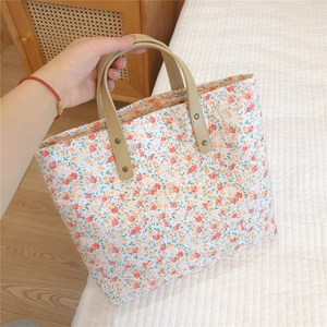 Detailed shot of floral tote bag with leather handle and metal rivet fastener