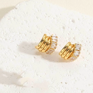 Macro detail of gold-plated hoop earrings with rectangular baguette zircon stones