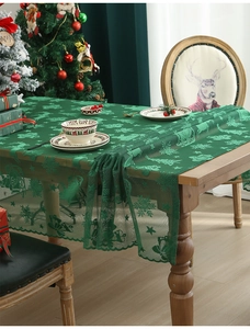 Detail of green lace tablecloth with woven Santa and reindeer Christmas patterns
