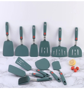 Detail of dark green silicone spatulas and brushes with stainless steel handles on marble
