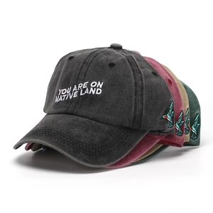 Detail of multi-color washed cotton baseball caps with hummingbird embroidery and text