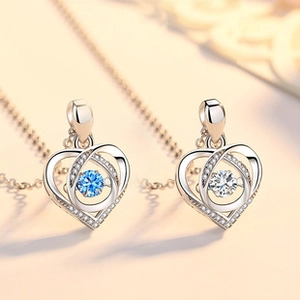 Macro shot of silver heart necklaces with blue and clear zircon stones in dancing setting