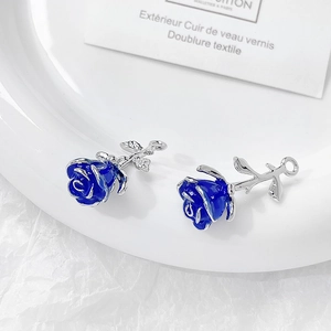 Detailed view of two blue rose charms with silver metal stems on a ceramic plate