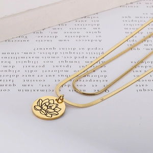 Dettaglio di collana doppia a catena serpente oro con pendente a fiore di loto inciso
