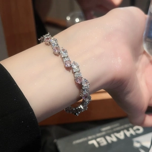 Detailed close-up of a silver bracelet featuring sparkling pink and white cubic zirconia stones