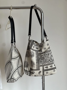 Detail of printed cotton linen tote bags with geometric and paisley patterns and leather straps