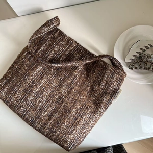 Detail of a brown tweed woven tote bag with a minimalist white simple wish brand label