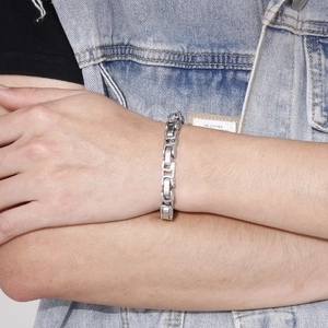Men's silver stainless steel chunky curb chain bracelet worn on a denim sleeve