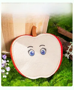 Detailed view of apple-shaped felt cat toy with stitching on mossy natural background