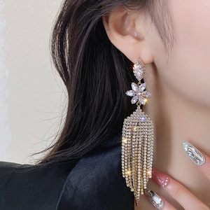 Close-up of gold tassel earrings with zircon flowers worn by a model for elegant look