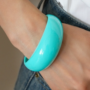 Close-up of a wide turquoise resin bangle bracelet worn on a wrist for a stylish look