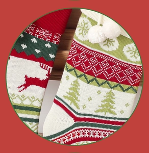 Close-up of knitted Christmas stockings with reindeer and tree patterns and white pom-poms