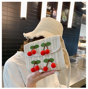 Straw shoulder bag with 3D cherry accents shown in a lifestyle restaurant setting