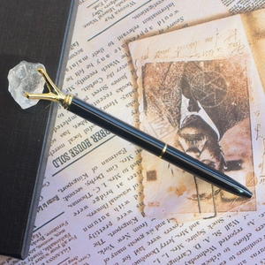 Détail d'un élégant stylo en cristal noir et doré sur un fond de journal vintage