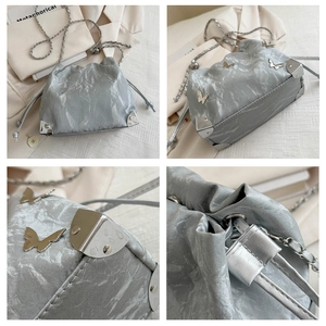 Detail of silver drawstring bag with metallic butterfly accents and textured finish