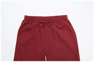Detailed close-up of dark burgundy sweatpants featuring elastic waist and drawstring