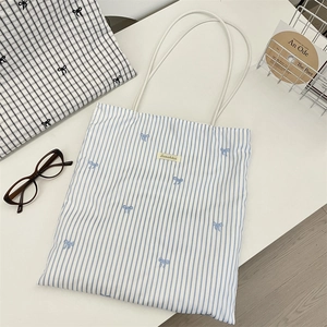 Detail of blue striped canvas tote bag with butterfly embroidery and brand label