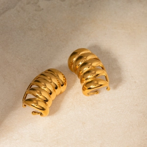 Macro view of 18K gold plated multi-layer spiral hoop earrings on a stone surface