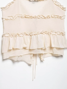 Detail view of cream ruffle knit camisole featuring layered tiers and drawstring hem