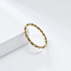 Macro detail of gold-plated twisted rope ring showing polished metallic texture on a white block