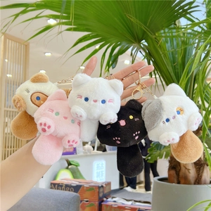 Set of five colorful plush cat keychains in white pink black and grey held by hand