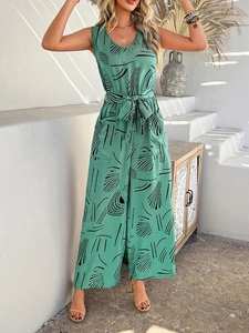 Detail of green sleeveless jumpsuit with black abstract print and belted waist design