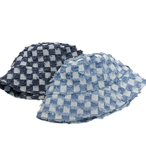 Detailed view of frayed edges on checkered denim bucket hats in dark and light blue