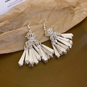 Detailed shot of silver tassel earrings with geometric prisms on textured paper