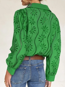 Close-up of green embroidery detail on back of long sleeve shirt with floral patterns