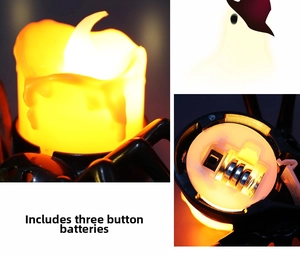Close-up of LED spider candle lamp showing warm flame effect and button battery compartment