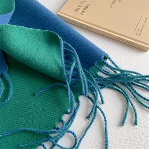 Detailed close-up of blue and green cashmere feel scarf showing soft texture and tassel fringe