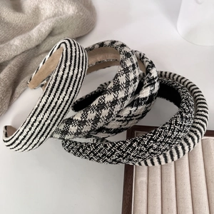 Four elegant black and white houndstooth and striped tweed sponge headbands on display