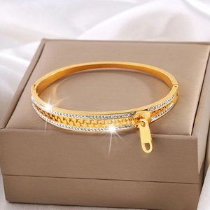 Close-up of golden zipper bangle with sparkling pavé crystals and polished metal charms