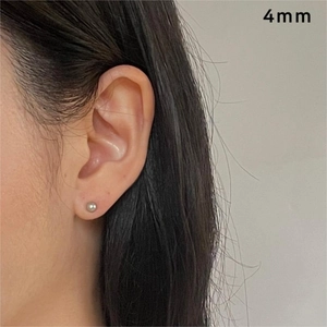 Close-up of 4mm silver bead stud earrings on ear showing scale and metallic luster