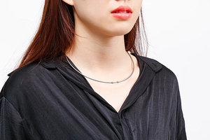 Minimalist silver stainless steel collar necklace with ball ends shown on a model