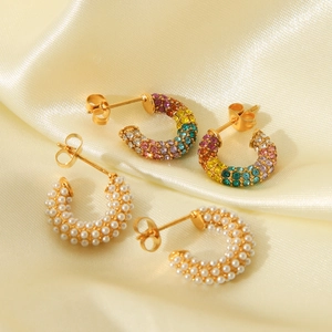 Elegant gold C-shaped earrings set with colorful zircons and white pearls on silk