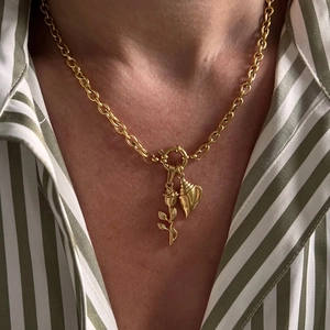Close-up of gold chain necklace with rose and seashell pendants on a female model