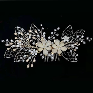 Detail of silver bridal hair comb with ivory flowers and crystal beads on black background