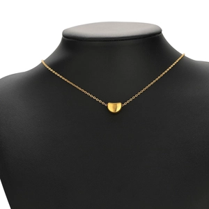 Detailed view of a gold bean-shaped pendant necklace on a black jewelry mannequin