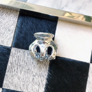 Detail of a shiny silver metallic hair claw clip on a stylish checkered fur surface